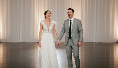 Bride and groom laughing on the dance floor with minimalist background.